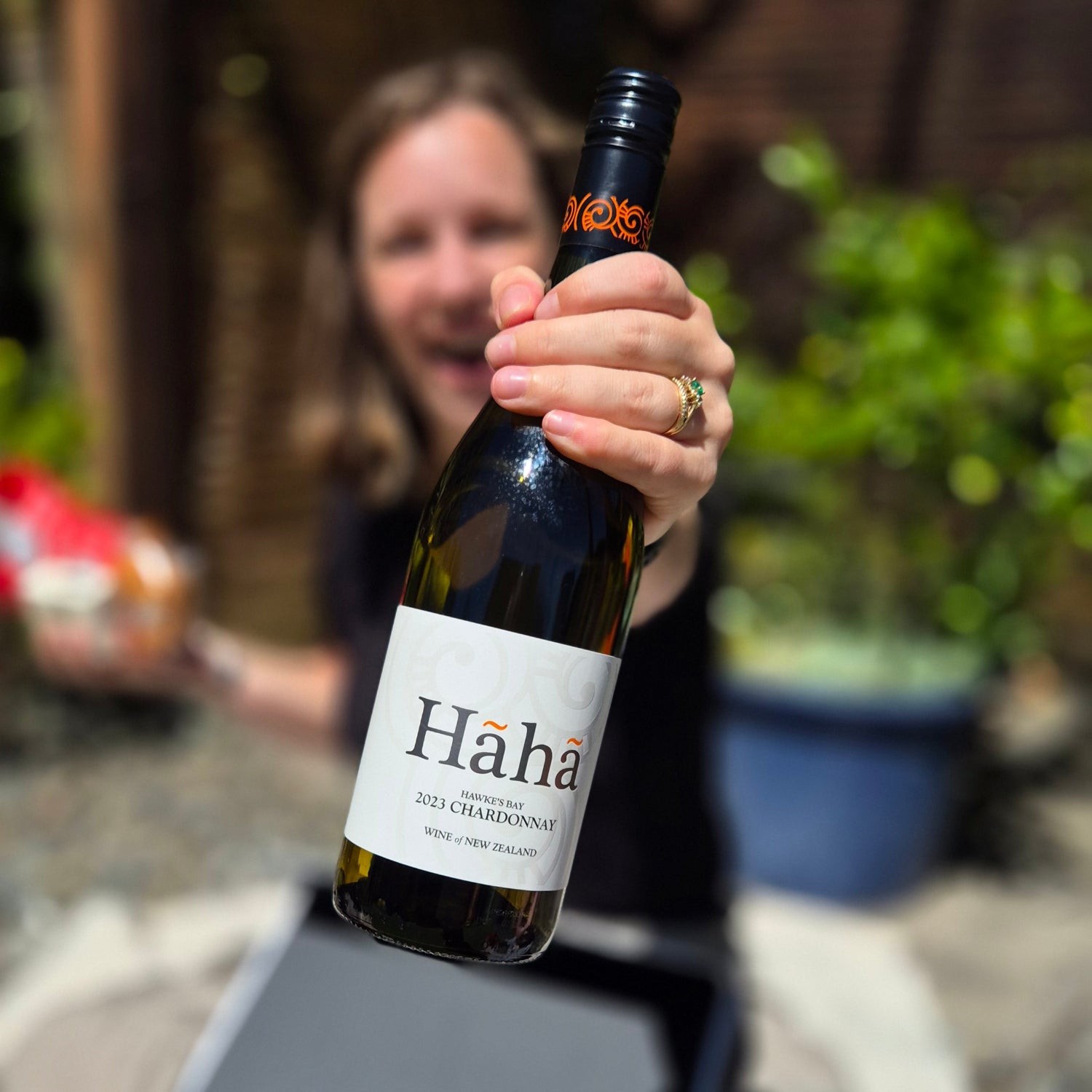 Lady opening a wickedly indulgent gift hamper showing off her haha wine with excitement.