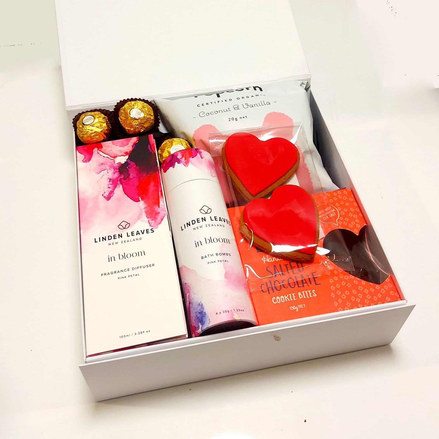In Bloom gift basket with room diffuser, bath bombs, gingerbread, cookies and popcorn all presented in a modern gift box.
