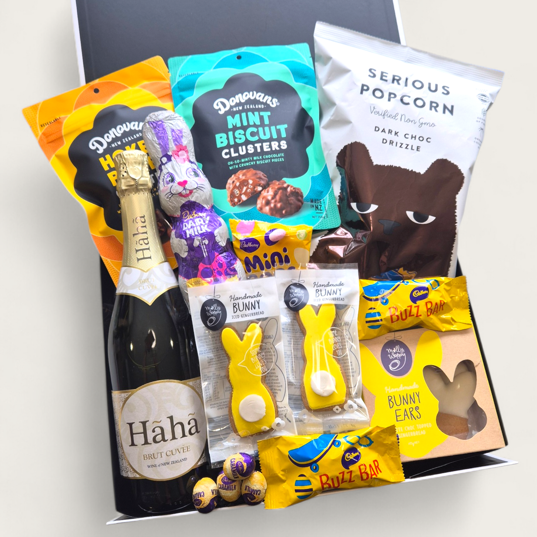 Easter gift hamper with sparkling wine, chocolate bunny, mini eggs, popcorn and sweet treats in a modern gift box