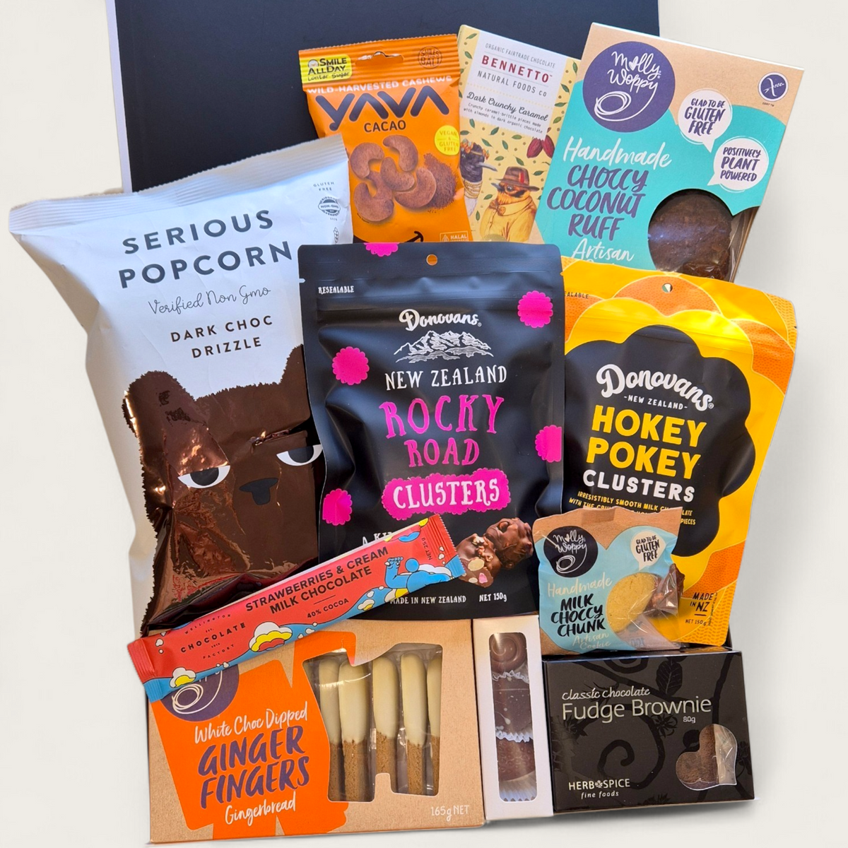 A premium gift hamper called "For Choc’s Sake" featuring chocolate treats including popcorn, cookies, rocky road, artisan  chocolate, borwnie, and cacao cashews in a sleek black & white Wickedly Indulgent box.