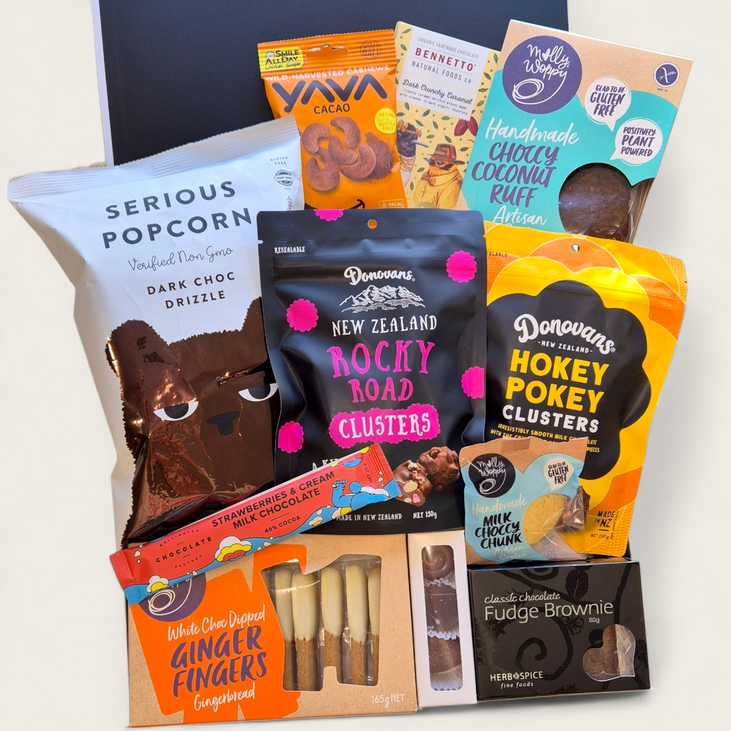 A premium gift hamper called "For Choc’s Sake" featuring chocolate treats including popcorn, cookies, rocky road, artisan  chocolate, borwnie, and cacao cashews in a sleek black & white Wickedly Indulgent box.