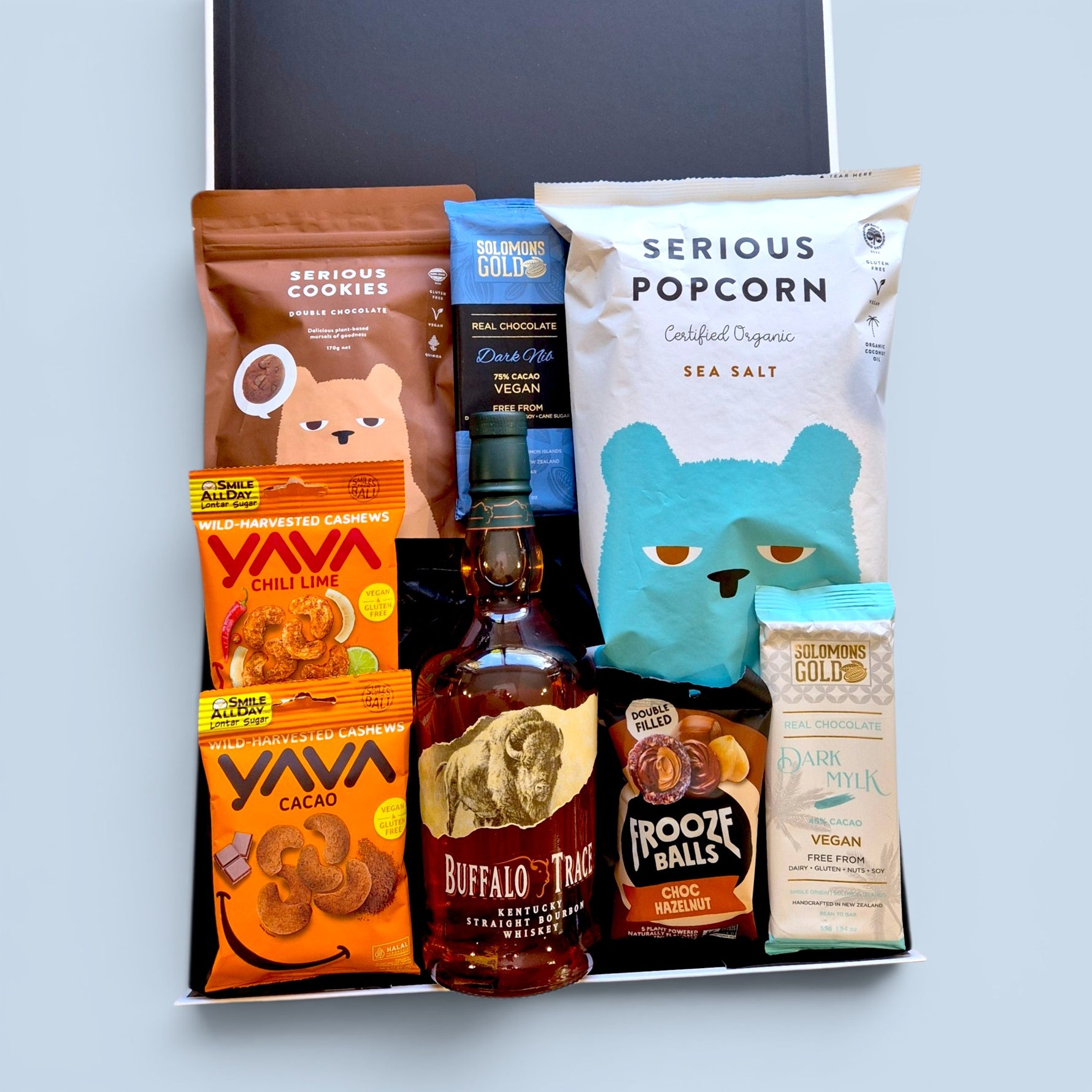 Gluten-free dairy-free gift hamper NZ containing Buffalo Trace Kentucky 
Straight Bourbon Whiskey, Serious Cookies Double Chocolate, Serious 
Popcorn Sea Salt, Solomon's Gold Dark Nib 75% Cacao vegan chocolate, 
Solomon's Gold Dark Mylk vegan chocolate, Yava Chilli Lime wild-harvested 
cashews, Yava Cacao cashews, and Frooze Balls Choc Hazelnut — 
Wickedly Indulgent you choose the booze gift box