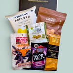 Snaccidents Happen gluten-free dairy-free gift box NZ. With Serious Popcorn, Serious Cookies Double Chocolate, Frooze Balls, Canterbury Biltong, green pitted olives, and Solomons dark chocolate