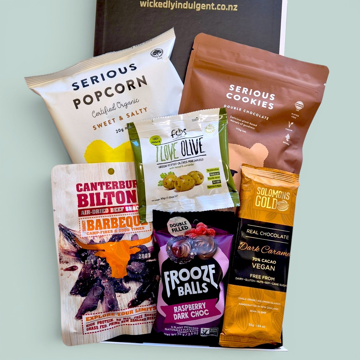 Snaccidents Happen gluten-free dairy-free gift box NZ. With Serious Popcorn, Serious Cookies Double Chocolate, Frooze Balls, Canterbury Biltong, green pitted olives, and Solomons dark chocolate