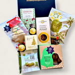 Festive Christmas hamper filled with premium snacks and treats including dark mint chocolate, caramel fudge, festive shortbread bells, Ferrero Rocher, savoury pretzels, olives, honey, brownie bite, and a decorated gingerbread tree cookie.
