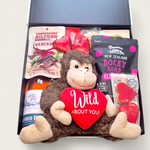 Love Gone Wild Gift Box featuring a 'Wild About You' monkey teddy, beer or wine, venison biltong, chocolate, gingerbread hearts, & fudge. A playful & fun Valentine’s Day hamper.