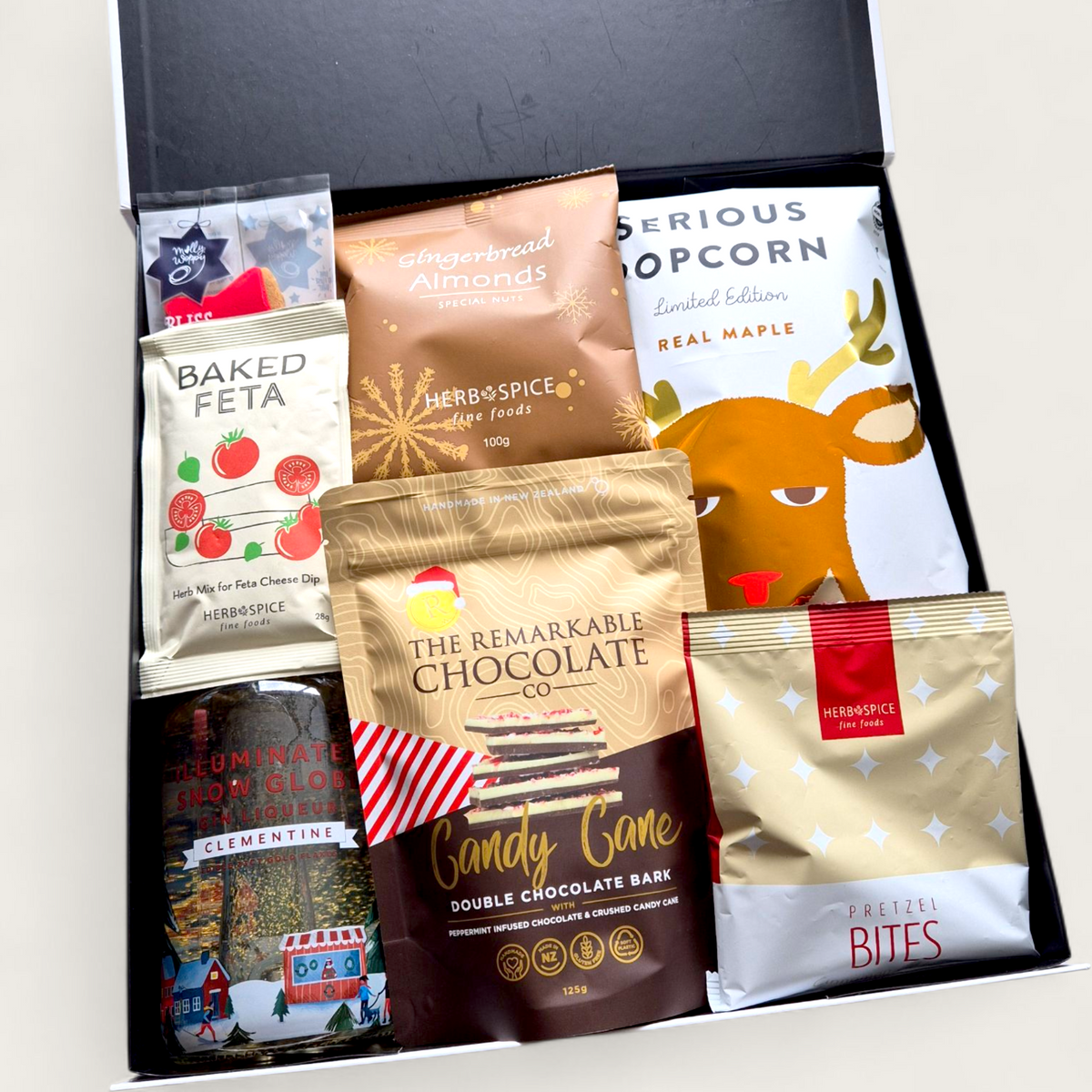 Let It Glow Snow Globe Gin Gift Box with LED-lit Clementine gin bottle, gold flakes, and artisan snacks in a festive black gift box.