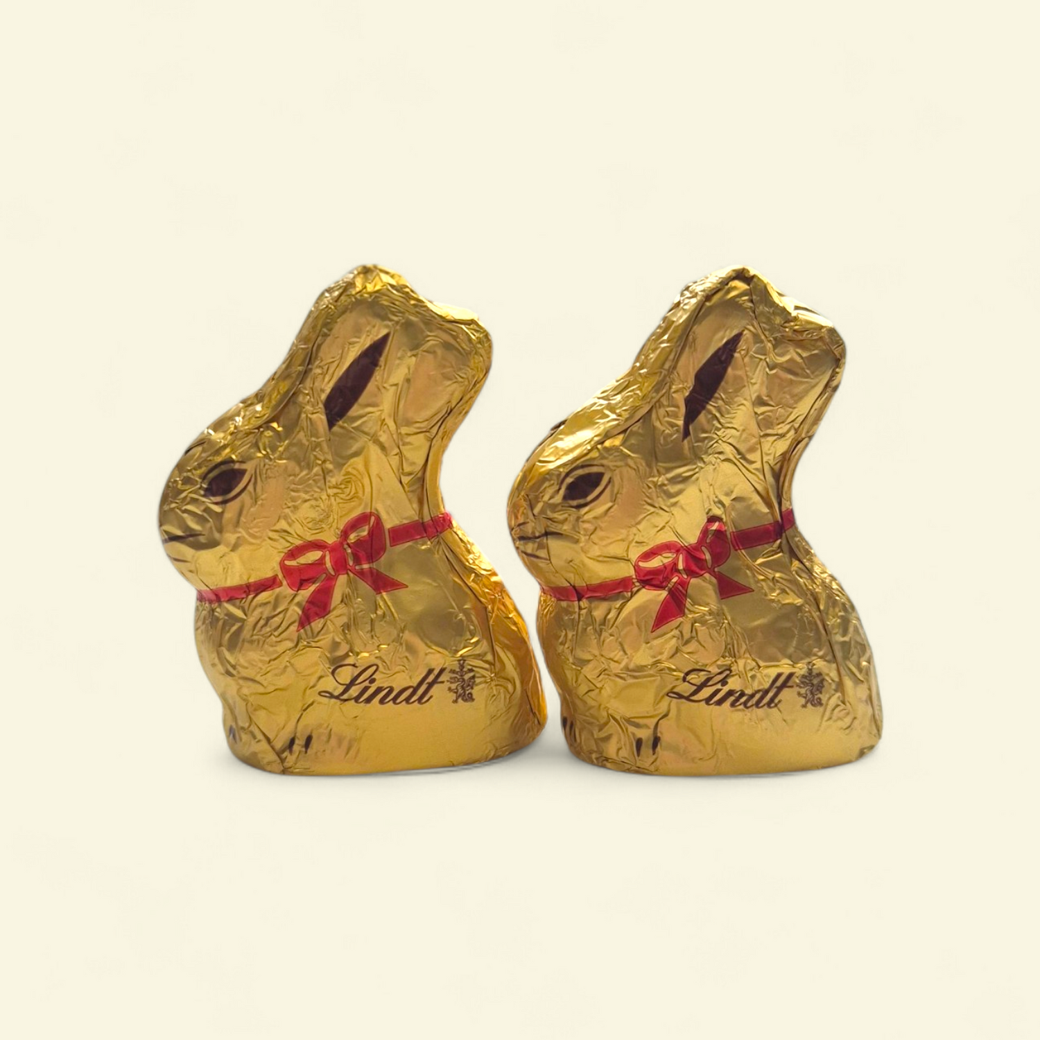 Two Lindt mini gold chocolate bunny figures wrapped in gold foil with red ribbon, perfect Easter gift box add-on.