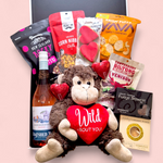 Love Gone Wild Gift Box featuring a 'Wild About You' monkey teddy, beer or wine, venison biltong, chocolate, gingerbread hearts, & fudge. A playful & fun Valentine’s Day hamper.