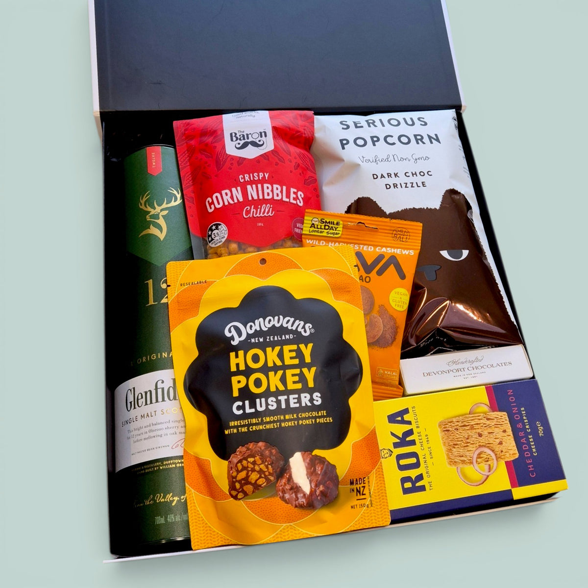 Wickedly Indulgent men's gift box with Glenfiddich whisky, popcorn, 
cacao cashews, cheese biscuits and snacks in a presented in a black and white wickedly indulgent box.
