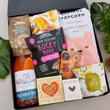 Cheers gift hamper with wine, popcorn, chocolate, fudge, brownie & nuts presented in a beautiful Gift Box.