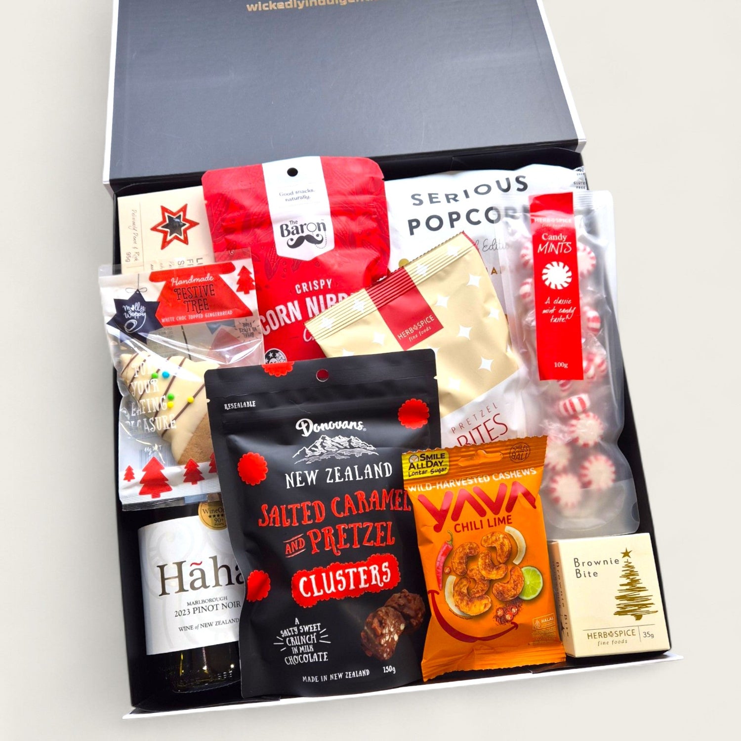 Christmas gift hamper “Sip, Snack & Sleigh” with NZ wine, gourmet popcorn, chilli cashews, pretzel bites, and festive sweets.