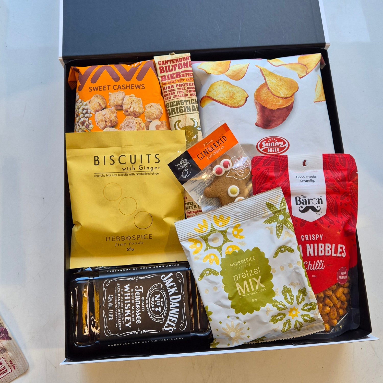 Gift box featuring Jack Daniel’s whiskey, gourmet snacks, corn nibbles, popcorn, and biscuits arranged in a black gift box – perfect for Father’s Day or gifting him.