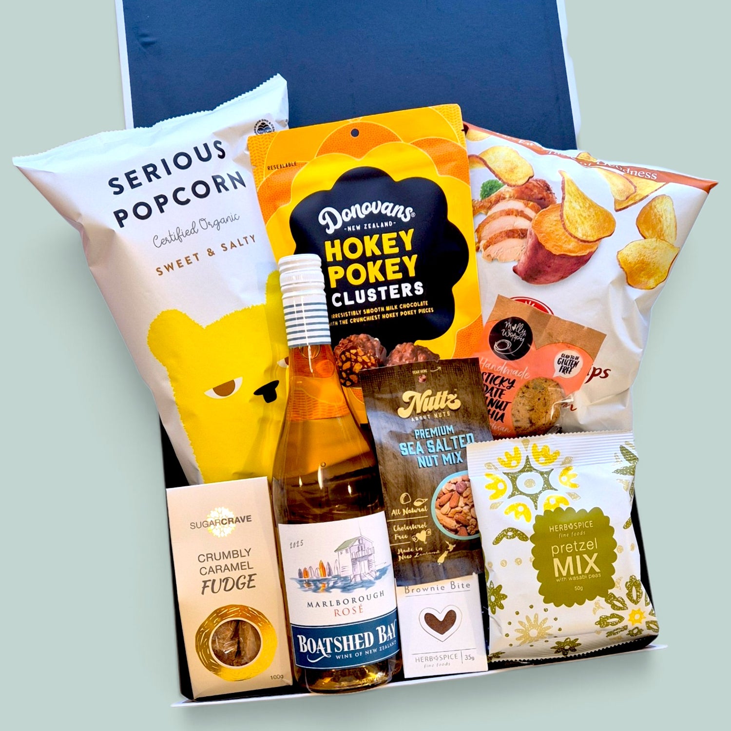 Cheers gift hamper with wine, popcorn, chocolate, fudge, brownie & nuts presented in a beautiful Gift Box.