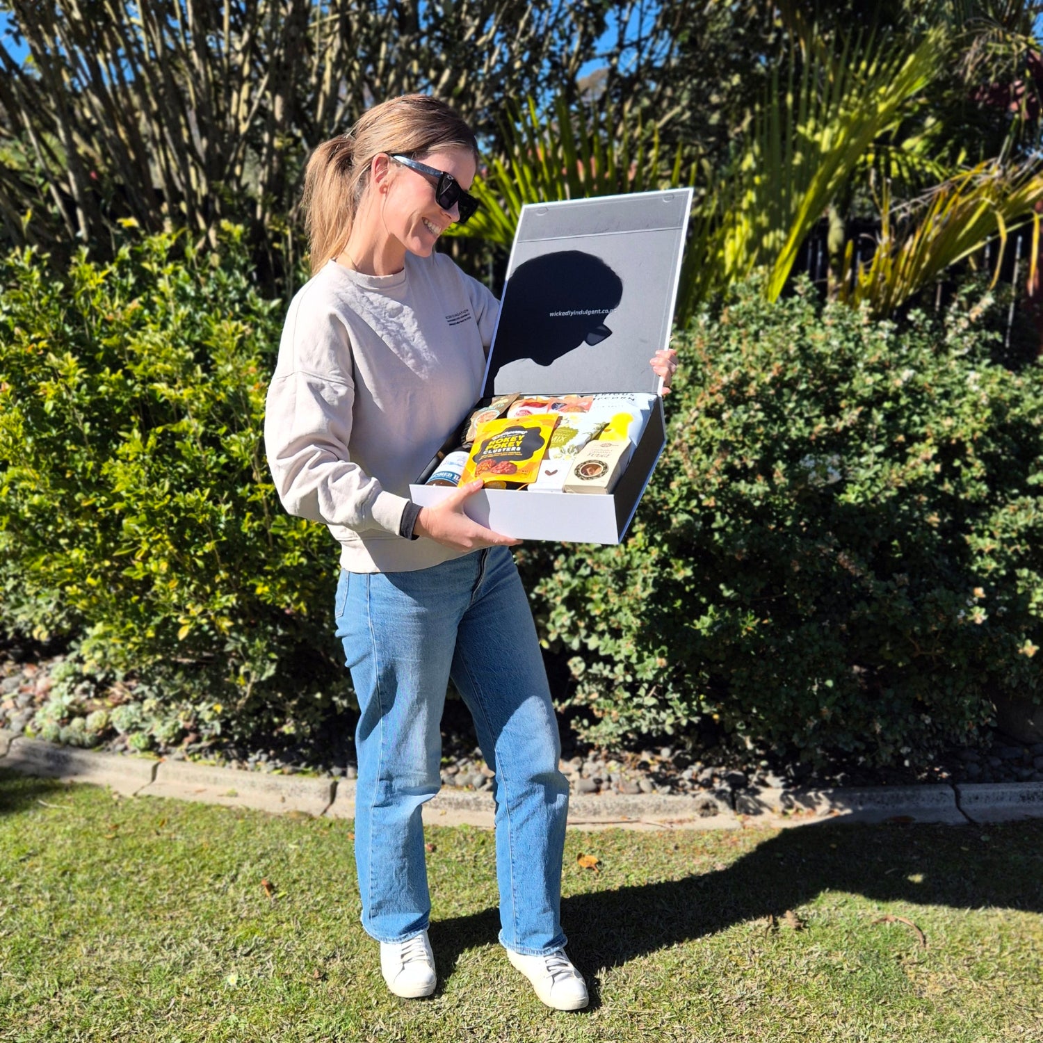 lady holding a gift box with wine and snacks