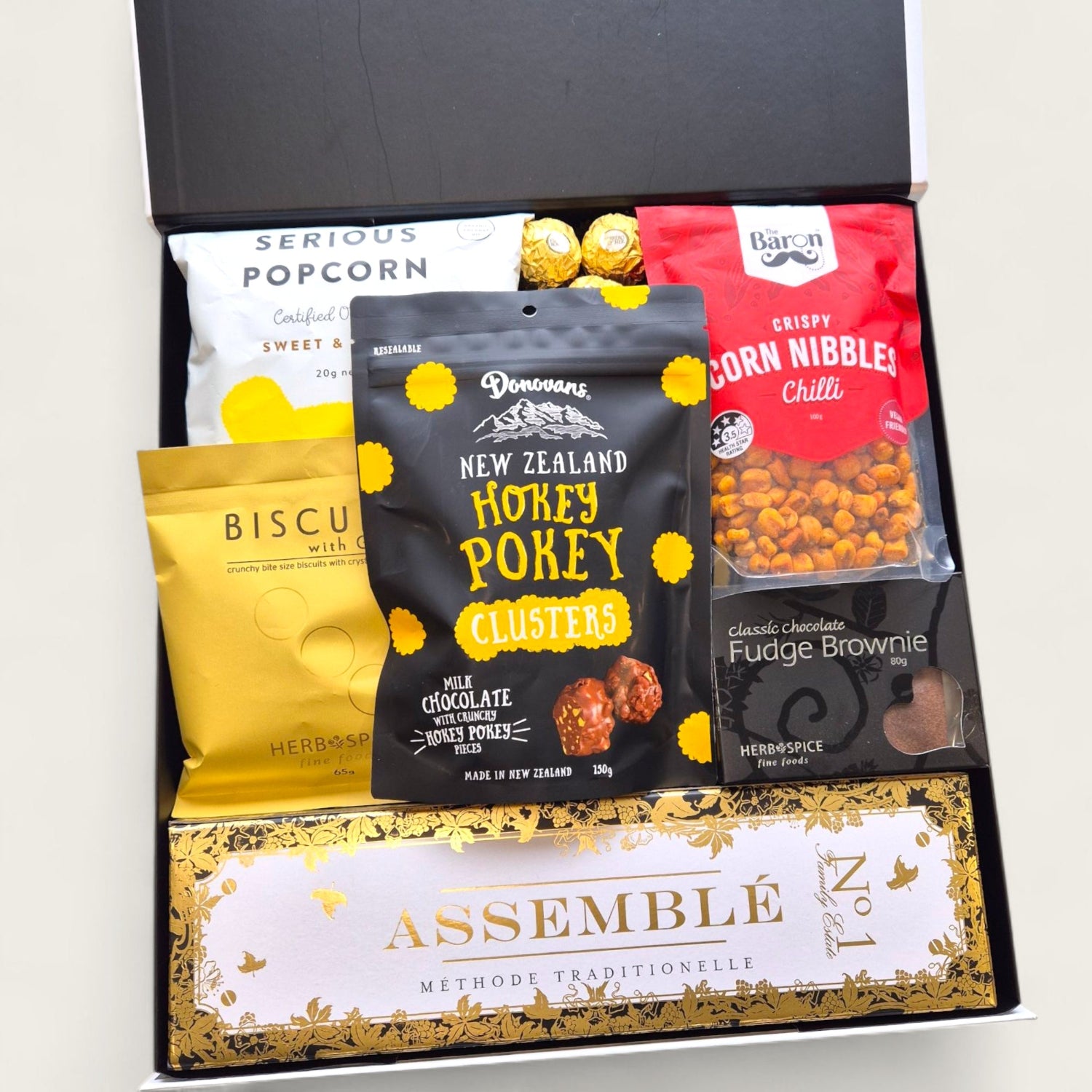 Champagne gift hamper with Assemble Brut, biscuits, popcorn, chocolate, and Ferrero Rocher in black and white box