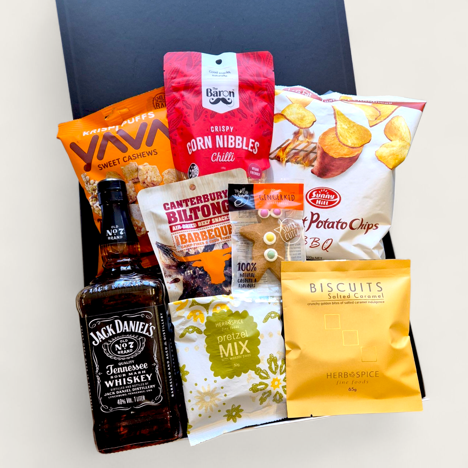 Gift box featuring Jack Daniel’s whiskey, gourmet snacks, corn nibbles, popcorn, and biscuits arranged in a black gift box – perfect for Father’s Day or gifting him.