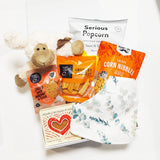 Baby Gift Basket with Soft Toy, Dribble Bib & yummy snacks. Presented in a modern Gift Box.