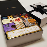 Celebration stash gift basket with champagne, chocolate, shortbread, plum paste and more presented in a modern gift box.